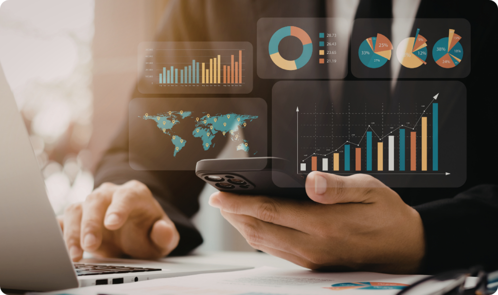 Close-up das mãos de um profissional em traje social utilizando um smartphone e um notebook simultaneamente. Sobrepostos à imagem, surgem diversos gráficos digitais flutuantes, incluindo mapas mundiais, gráficos de barras de crescimento, gráficos de pizza e indicadores financeiros, representando o monitoramento móvel de dados.