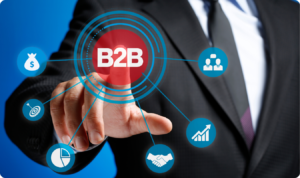 Um homem vestindo um terno preto e gravata está em destaque contra um fundo azul sólido. Ele estende a mão para tocar um botão digital central flutuante com o texto "B2B" em branco dentro de um círculo vermelho. Deste círculo central, partem linhas que se conectam a seis ícones circulares azuis menores, representando diferentes pilares estratégicos: um saco de dinheiro (lucratividade), um alvo com uma seta (metas/conversão), um gráfico de pizza (análise de dados), um aperto de mãos (parcerias/vendas), um megafone (marketing) e silhuetas de pessoas (networking/clientes).